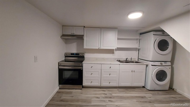 kitchen featuring stacked washer / dryer, open shelves, under cabinet range hood, stainless steel range with electric stovetop, and a sink