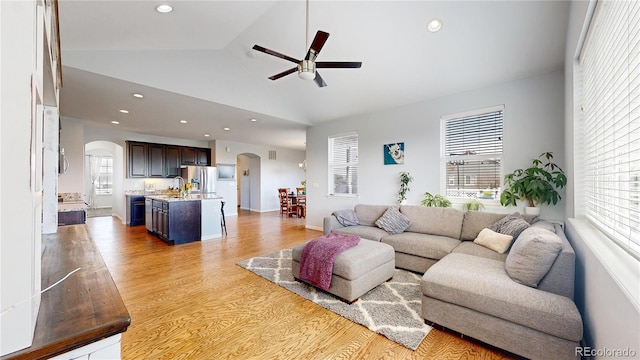 living room with lofted ceiling, sink, ceiling fan, and light hardwood / wood-style flooring