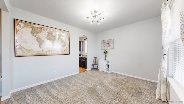 unfurnished room featuring light colored carpet and a chandelier