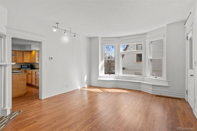 613 Pine St, Boulder, CO 80302 - unfurnished living room with visible vents, light wood-type flooring, baseboards, and decorative columns