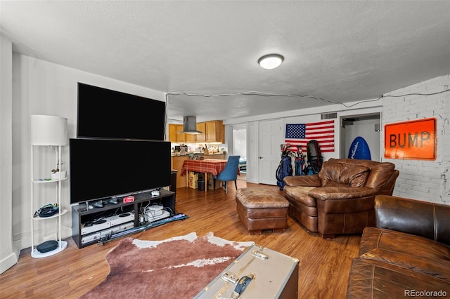 613 Pine St, Boulder, CO 80302 - living area with visible vents, a textured ceiling, brick wall, and light wood finished floors