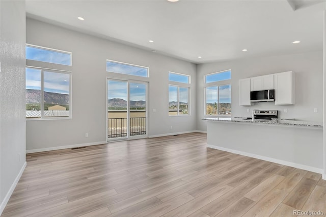 241 N Front St Unit 103, Monument, CO 80132 - unfurnished living room featuring recessed lighting, baseboards, a wealth of natural light, and light wood-type flooring