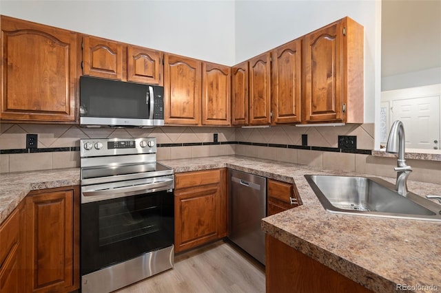 1460 Front Nine Dr Unit A, Fort Collins, CO 80525 - kitchen featuring stainless steel appliances, brown cabinets, light wood finished floors, and backsplash