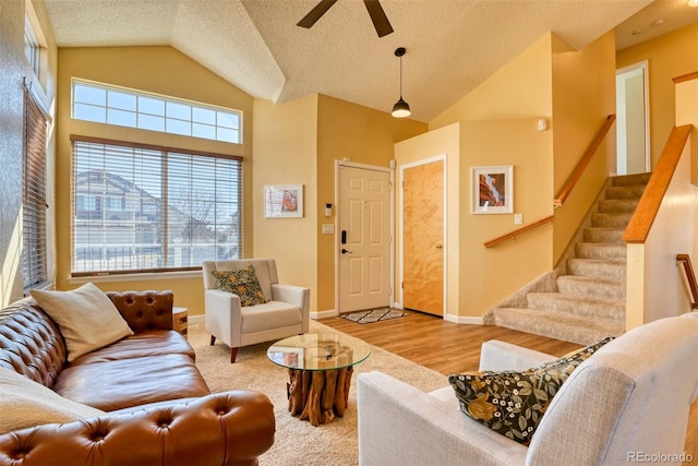 living room featuring ceiling fan, high vaulted ceiling, a textured ceiling, and light wood-type flooring