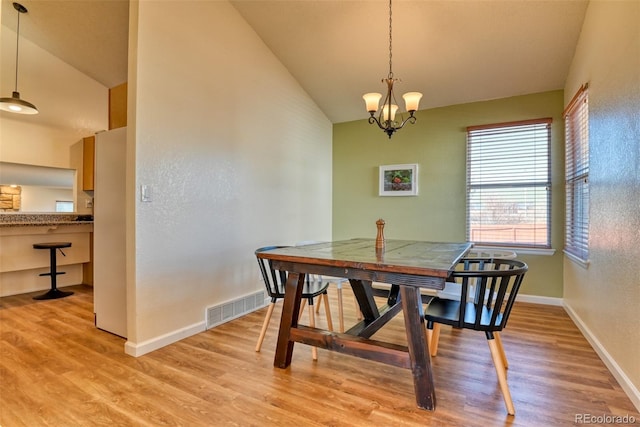 dining area with vaulted ceiling, a chandelier, and light wood-type flooring