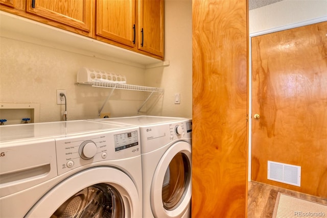 clothes washing area with cabinets and washer and dryer