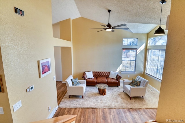 living room featuring high vaulted ceiling, a textured ceiling, light hardwood / wood-style floors, and ceiling fan