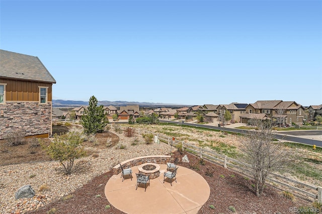 view of yard featuring a patio, an outdoor fire pit, fence, and a residential view