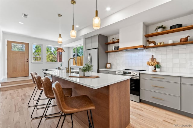 1046 N Knox Ct, Denver, CO 80204 - kitchen featuring stainless steel appliances, gray cabinetry, open shelves, custom range hood, and light countertops