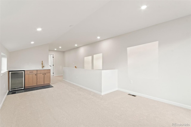 1046 N Knox Ct, Denver, CO 80204 - empty room with light carpet, bar with sink, beverage cooler, recessed lighting, and vaulted ceiling