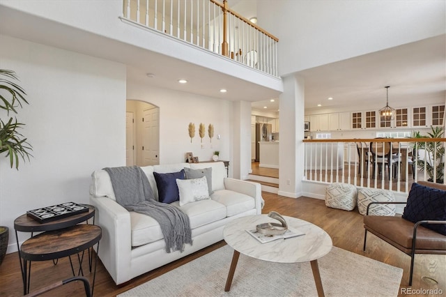 4526 Lyndenwood Pt, Highlands Ranch, CO 80130 - living room featuring wood finished floors, arched walkways, recessed lighting, a high ceiling, and a chandelier