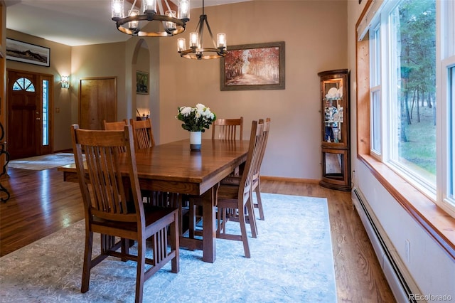 33 Sparrow Ct, Bailey, CO 80421 - dining area featuring baseboard heating, a chandelier, arched walkways, and light wood-style floors