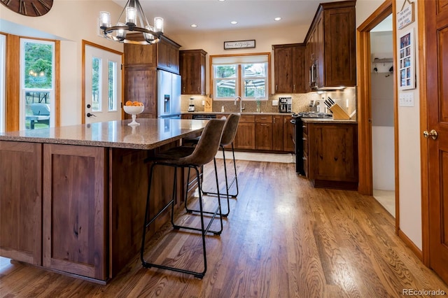 33 Sparrow Ct, Bailey, CO 80421 - kitchen featuring black range, white fridge with ice dispenser, wood finished floors, tasteful backsplash, and a chandelier