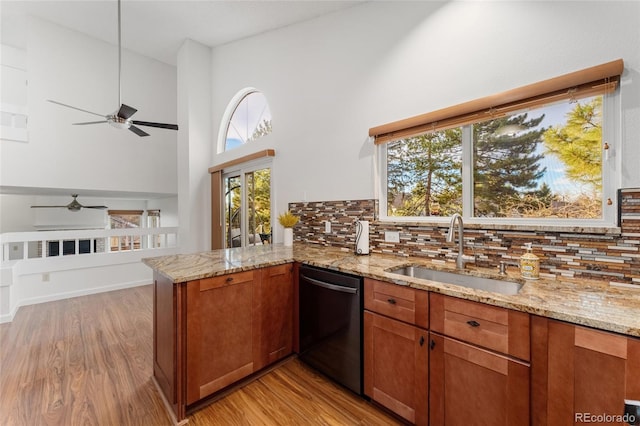 kitchen featuring kitchen peninsula, decorative backsplash, stainless steel dishwasher, sink, and light hardwood / wood-style floors