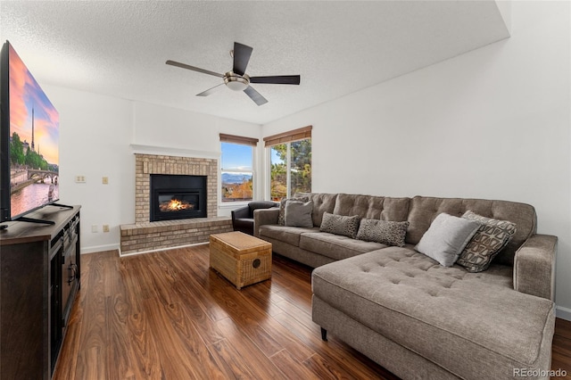 living room with ceiling fan, a fireplace, dark hardwood / wood-style floors, and a textured ceiling