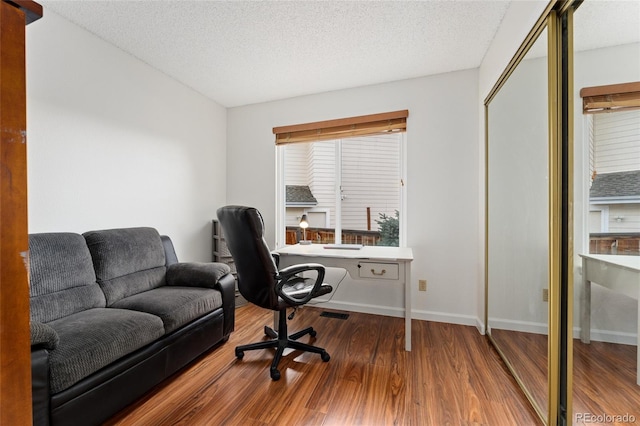 home office with wood-type flooring and a textured ceiling