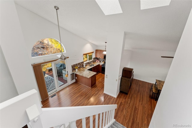 stairs featuring a skylight, ceiling fan, high vaulted ceiling, and wood-type flooring