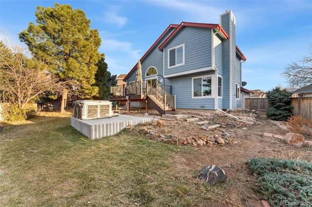 back of property featuring a wooden deck and a lawn