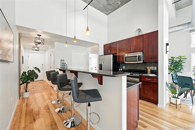2518 16th St, Denver, CO 80211 - kitchen featuring stainless steel appliances, light wood-style floors, a kitchen bar, tasteful backsplash, and decorative light fixtures