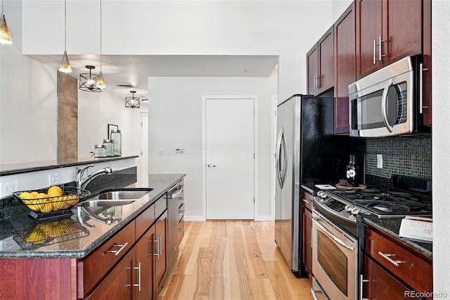 2518 16th St, Denver, CO 80211 - kitchen with appliances with stainless steel finishes, a sink, light wood-style floors, backsplash, and dark stone counters