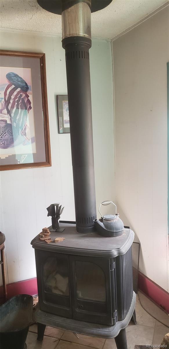 room details with a textured ceiling, tile patterned flooring, and a wood stove