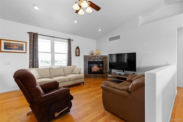 living room featuring ceiling fan, a tile fireplace, light hardwood / wood-style flooring, and lofted ceiling