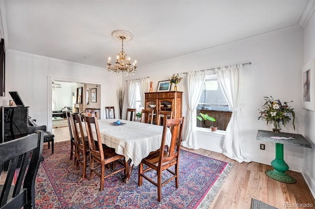 dining space featuring wood-type flooring, crown molding, and an inviting chandelier