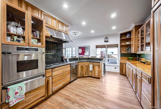 kitchen featuring sink, tasteful backsplash, light wood-type flooring, appliances with stainless steel finishes, and kitchen peninsula