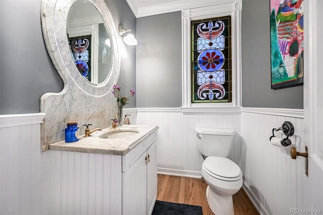 bathroom with crown molding, wood-type flooring, toilet, and vanity