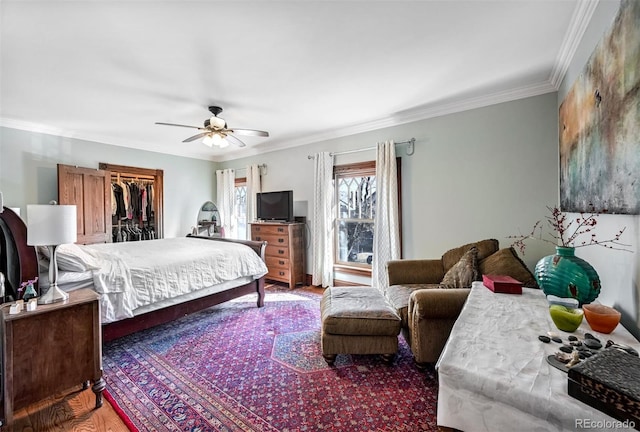 bedroom featuring hardwood / wood-style flooring, ornamental molding, a spacious closet, ceiling fan, and a closet