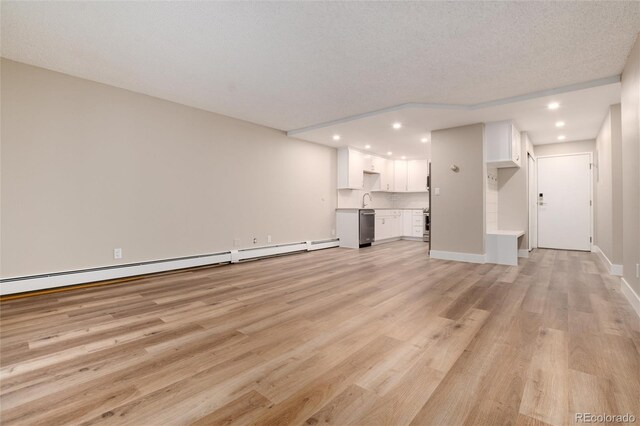 unfurnished living room with sink, baseboard heating, a textured ceiling, and light hardwood / wood-style flooring