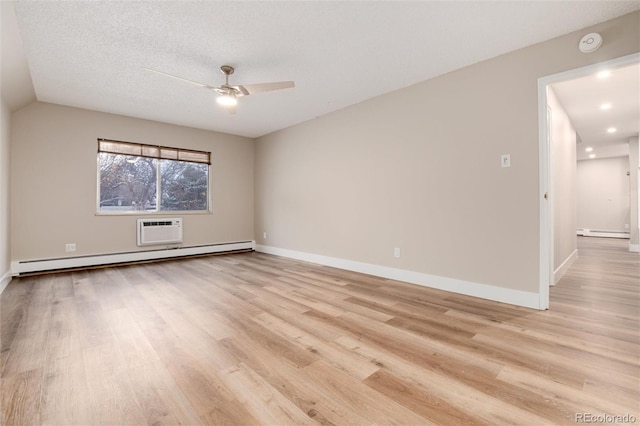 spare room featuring a textured ceiling, a wall unit AC, ceiling fan, baseboard heating, and light hardwood / wood-style floors