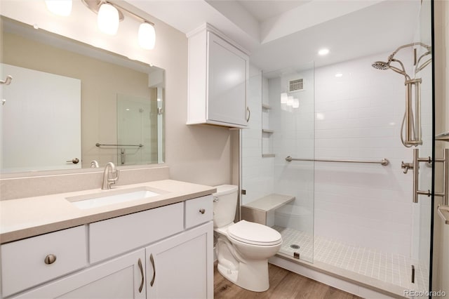 bathroom featuring vanity, hardwood / wood-style flooring, toilet, and walk in shower