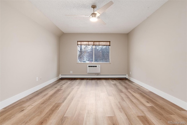 empty room featuring a textured ceiling, a wall mounted AC, ceiling fan, a baseboard radiator, and light hardwood / wood-style floors