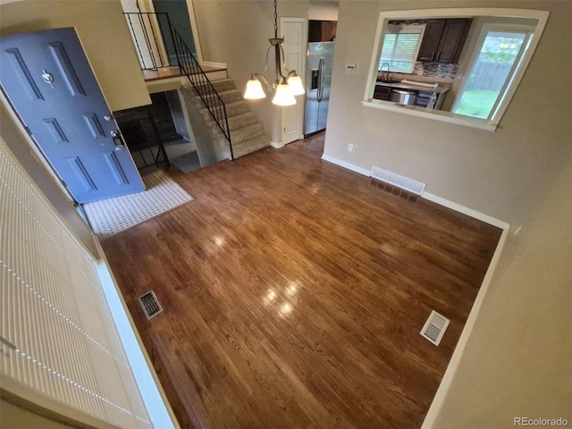 1962 S Ivory Way, Aurora, CO 80013 - unfurnished living room with dark wood-type flooring, a sink, stairs, baseboards, and a chandelier