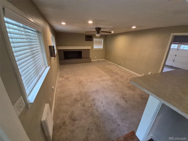 1962 S Ivory Way, Aurora, CO 80013 - unfurnished living room featuring ceiling fan, a fireplace with raised hearth, recessed lighting, light colored carpet, and baseboards
