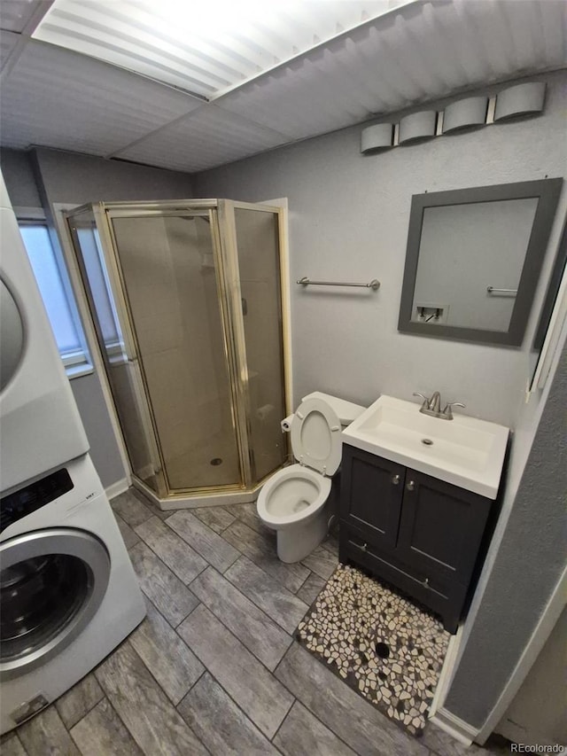 1962 S Ivory Way, Aurora, CO 80013 - full bathroom with stacked washer / dryer, a shower stall, vanity, toilet, and wood tiled floors