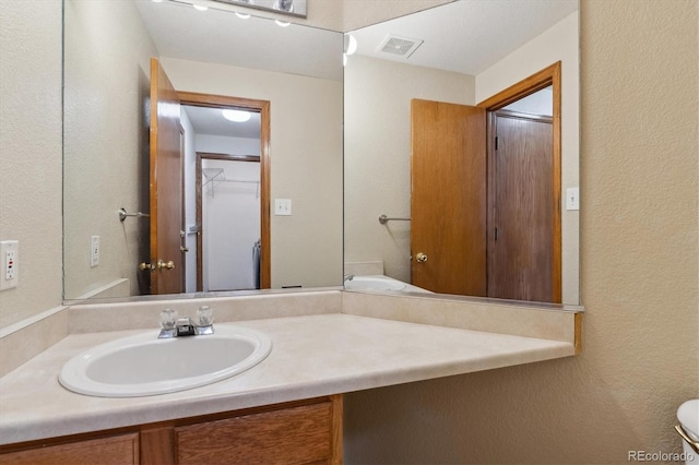 bathroom with vanity, a textured wall, and visible vents