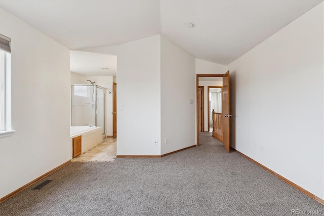 interior space featuring light carpet, baseboards, vaulted ceiling, and visible vents