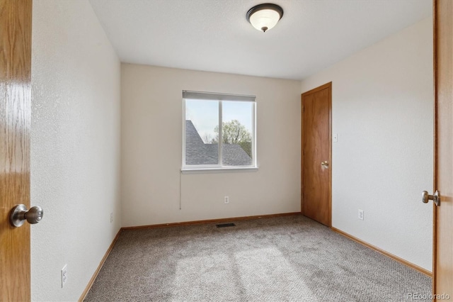 carpeted empty room featuring baseboards and visible vents