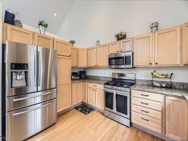 11526 Green Cir, Conifer, CO 80433 - kitchen with appliances with stainless steel finishes, light brown cabinetry, high vaulted ceiling, light wood finished floors, and dark stone counters