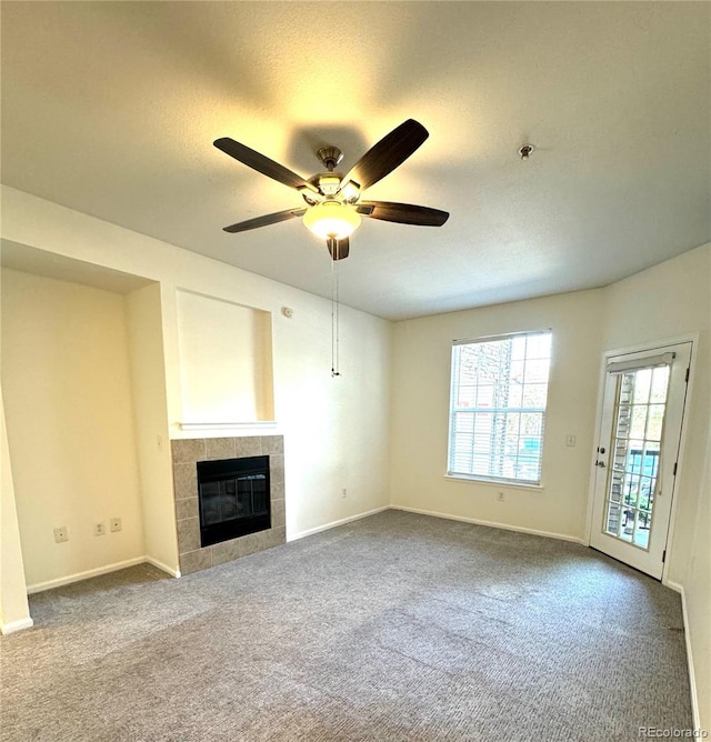 unfurnished living room with a tile fireplace, ceiling fan, and carpet