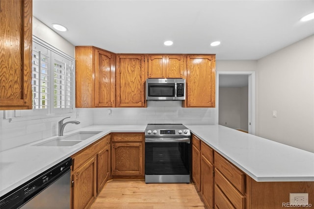 888 E Davies Ave, Centennial, CO 80122 - kitchen featuring stainless steel appliances, a peninsula, light wood-style flooring, light countertops, and brown cabinets