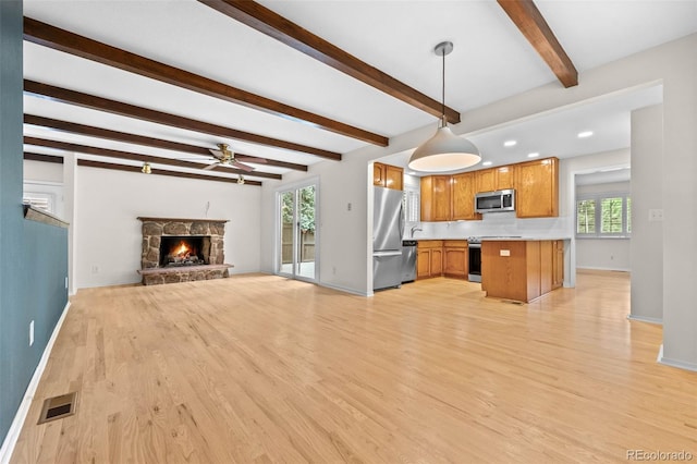 888 E Davies Ave, Centennial, CO 80122 - unfurnished living room featuring light wood-type flooring, a ceiling fan, healthy amount of natural light, beamed ceiling, and a fireplace
