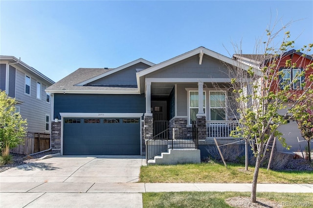 craftsman house featuring fence, stone siding, a garage, a porch, and driveway