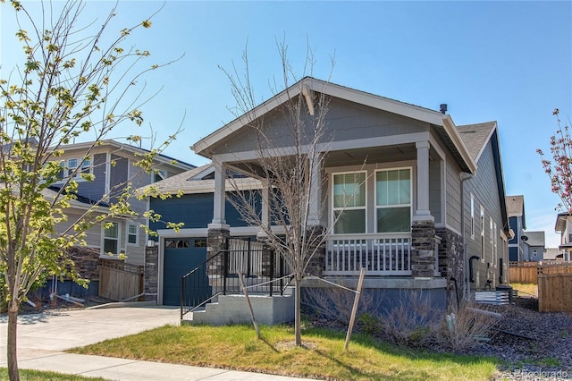 view of front of property with fence, an attached garage, stone siding, a porch, and driveway