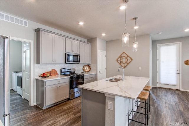 kitchen with a sink, visible vents, stainless steel appliances, gray cabinetry, and dark wood-style floors