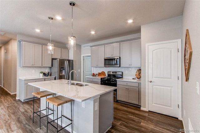 kitchen featuring gray cabinets, backsplash, visible vents, appliances with stainless steel finishes, and a sink