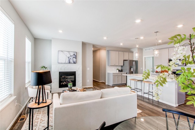 living area with visible vents, a fireplace, baseboards, recessed lighting, and light wood-style flooring