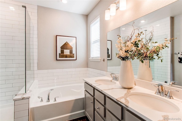 bathroom with double vanity, a sink, and a bath